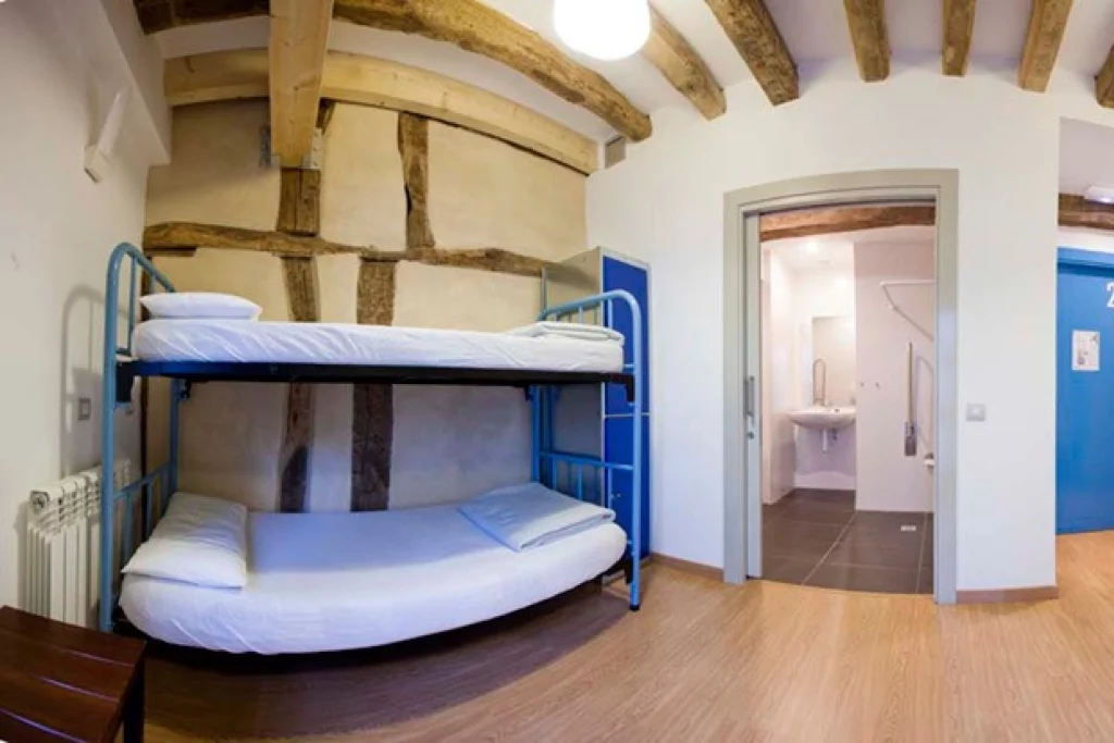 Habitación con literas en un albergue, baño al fondo