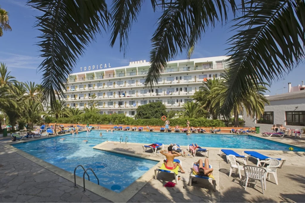 Hotel tropical con piscina grande y palmeras en un día soleado