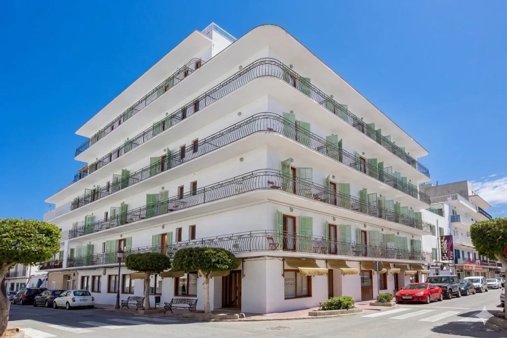 Foto de un edificio blanco de varios pisos con balcones y un entorno urbano