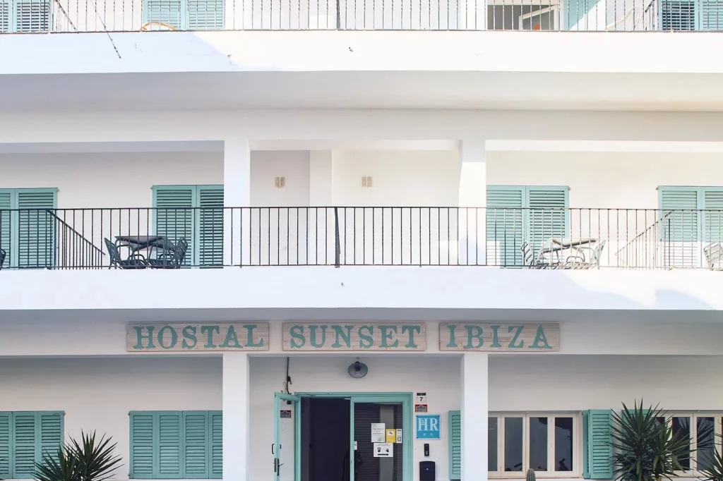 Fachada del Hostal Sunset Ibiza en Ibiza con balcón y señal de bienvenida